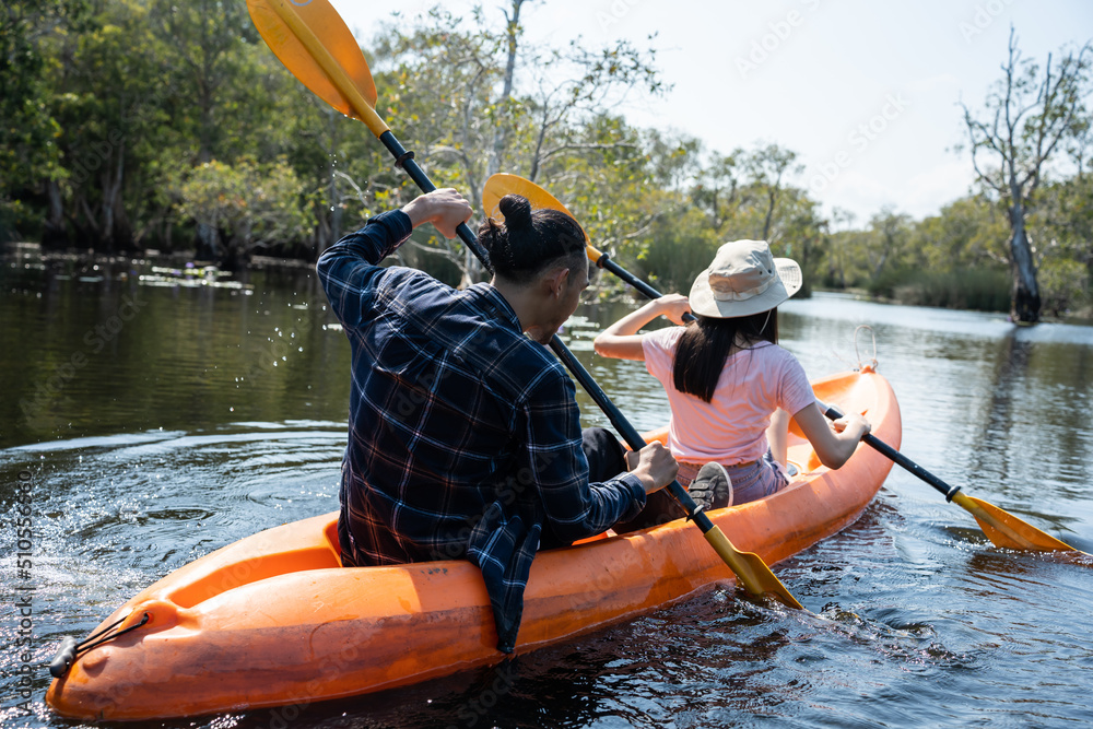 Asian attractive romantic young couple rowing kayak in a forest lake. 