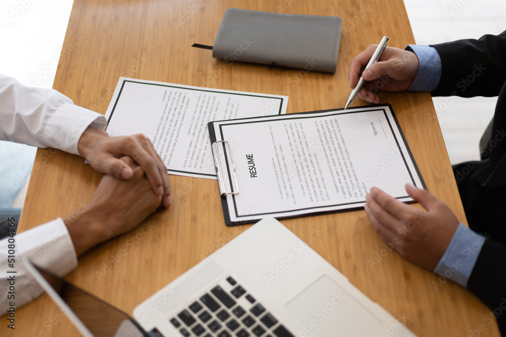 The manager holding the papers is reading the resume and interviewing the applicant or new employee 