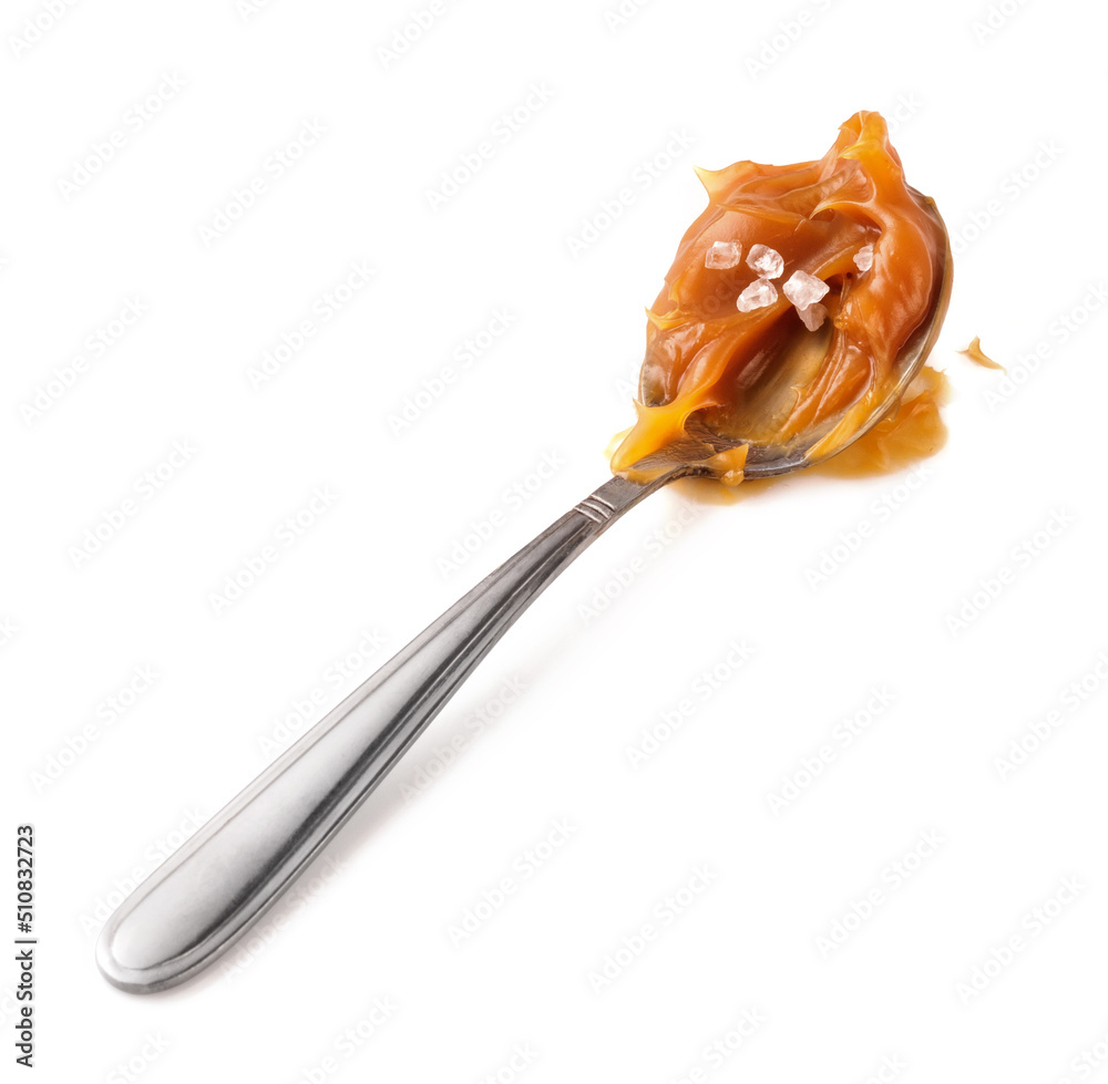 Soft caramel on metal spoon isolated on white background. Caramel sauce.