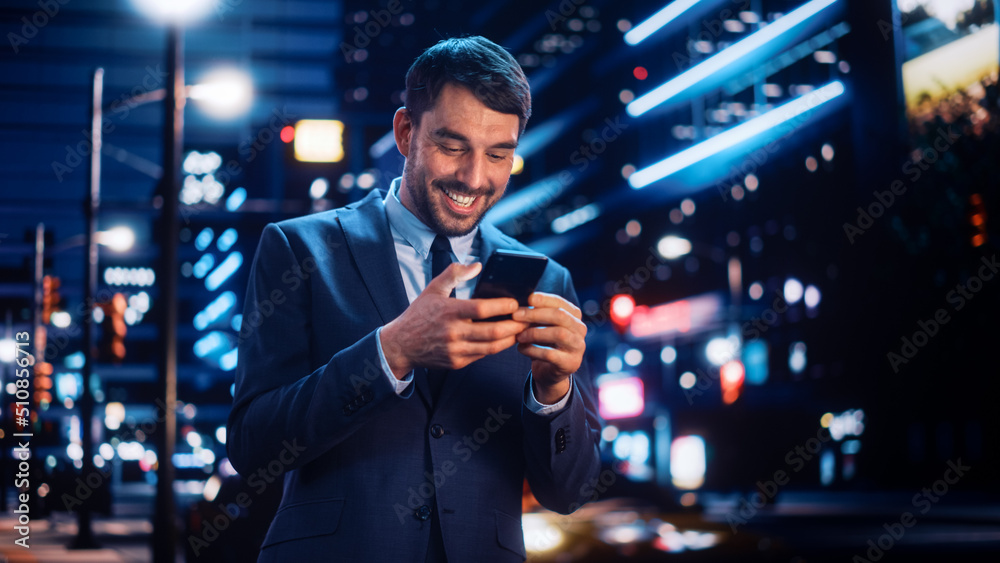 Portrait of a Handsome Man in Stylish Suit Walking in a Modern City Street with Neon Lights at Night