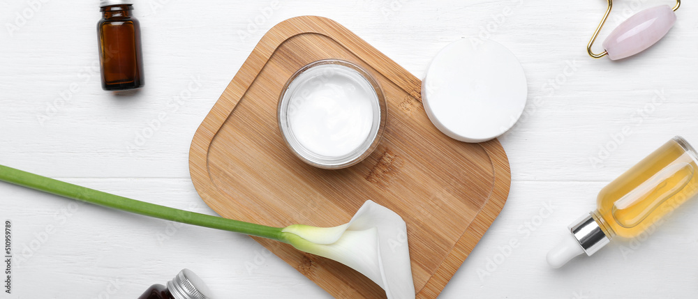 Set of cosmetic products and calla lily on white wooden background