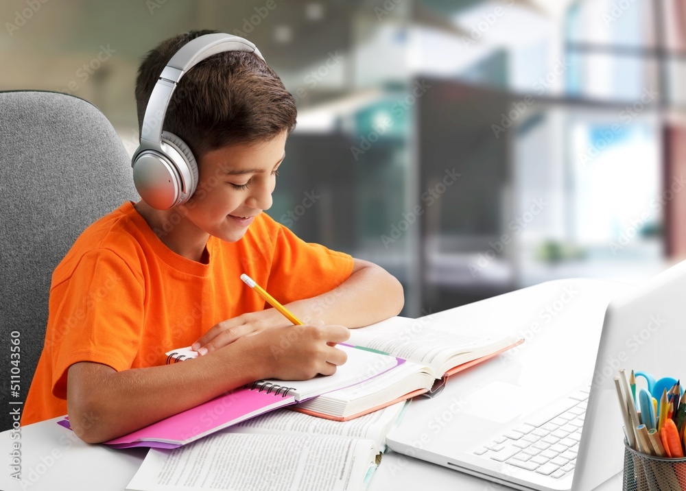 Smiling intelligent schooler teen doing homework, sitting at table, enjoying educational process