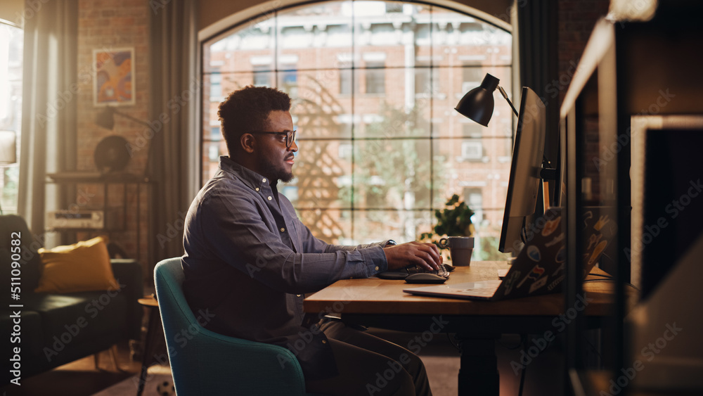 Young Handsome African American Man Working from Home on Desktop Computer in Sunny Stylish Loft Apar