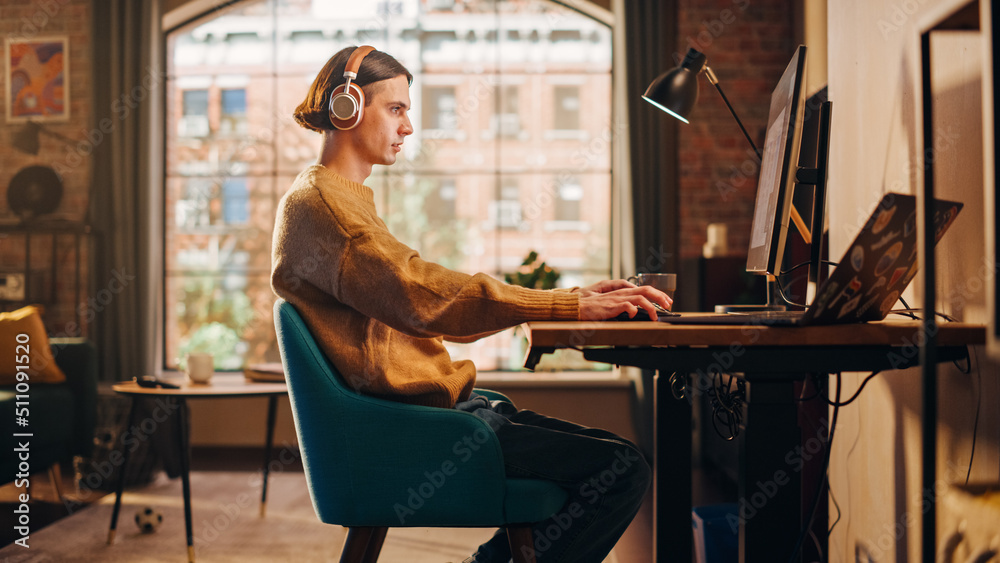 Young Handsome Man Working from Home on Desktop Computer in Sunny Stylish Loft Apartment. Creative D