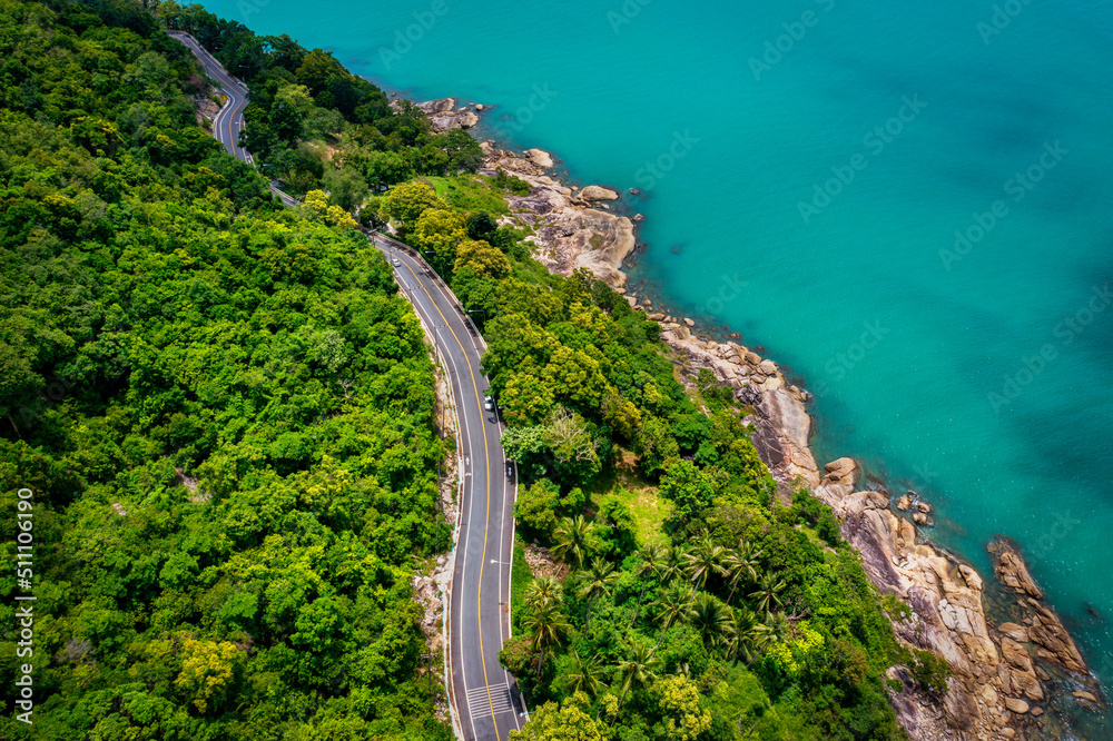 Aerial view of road between coconut palm tree and great ocean at daytime in Nakhon Si Thammarat, Tha