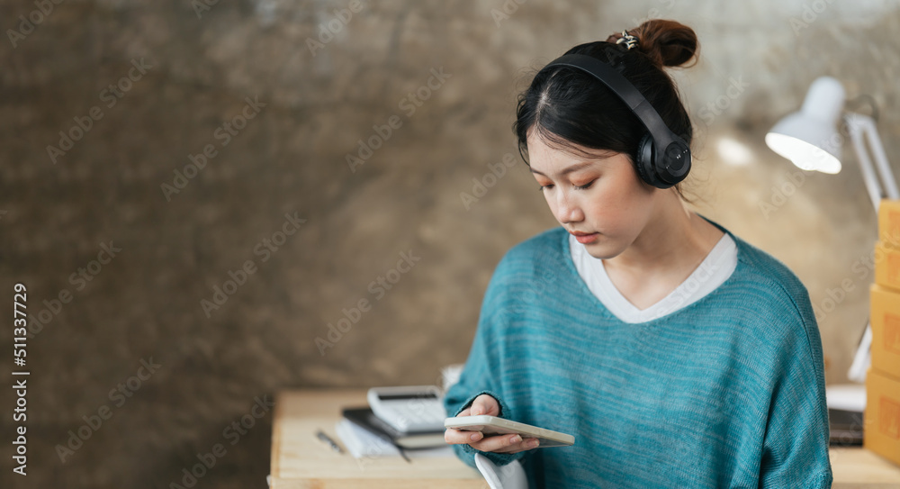 Peaceful girl in modern wireless headphones sit relax on comfortable couch listening to music, Asian