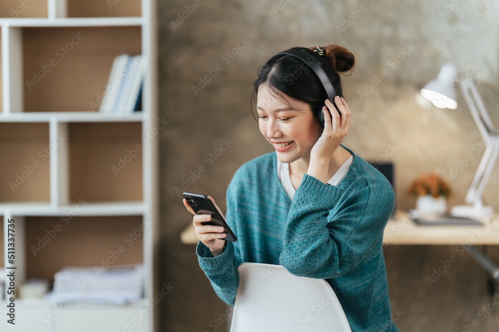 戴着现代无线耳机的宁静女孩坐在舒适的沙发上放松，听音乐，亚洲人