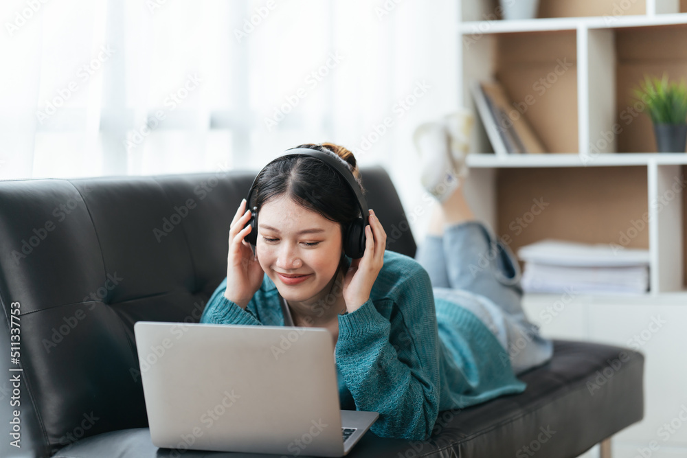 戴着耳机微笑的美丽年轻女子在家通过笔记本电脑视频通话聊天