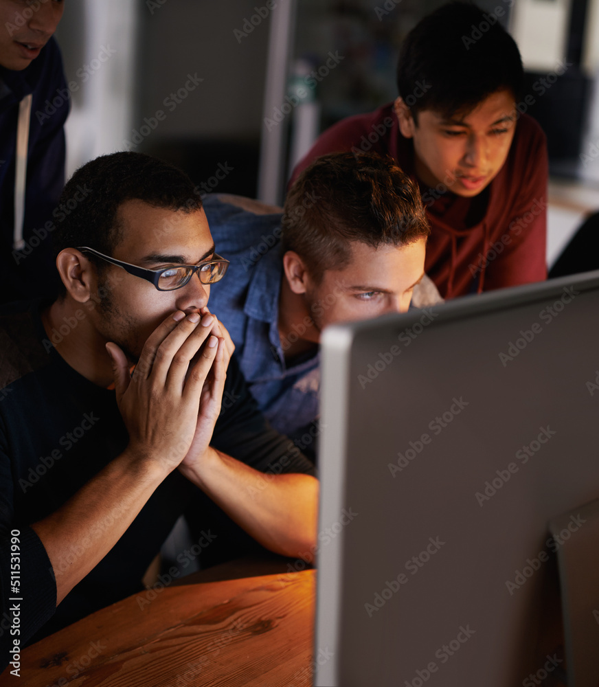 This is insane. Shot of a group of young designers staring tensely at a monitor.