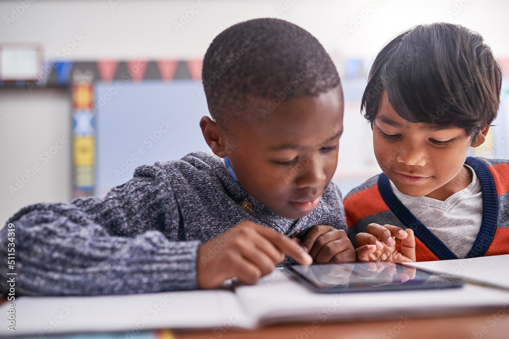 Two heads are better than one. Cropped shot of elementary school children using a tablet in class.