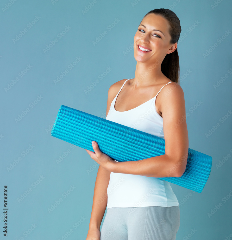 Im never late for yoga class. Studio portrait of a healthy young woman holding an exercise mat again