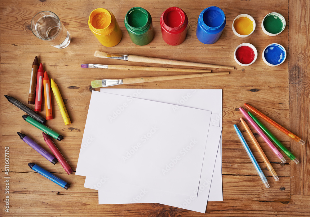 Creativity never goes out of style. Blank white paper with painting supplies and pencils on a wooden