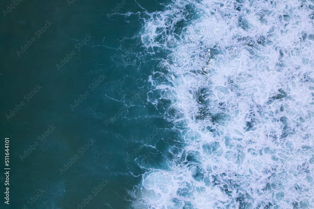 Sea blue surface aerial view.Top view blue water ocean waves with white foam background