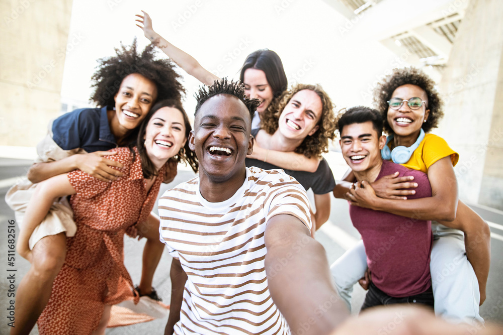 Multiracial friends taking selfie group picture with smart mobile phone outside on city street - Hap