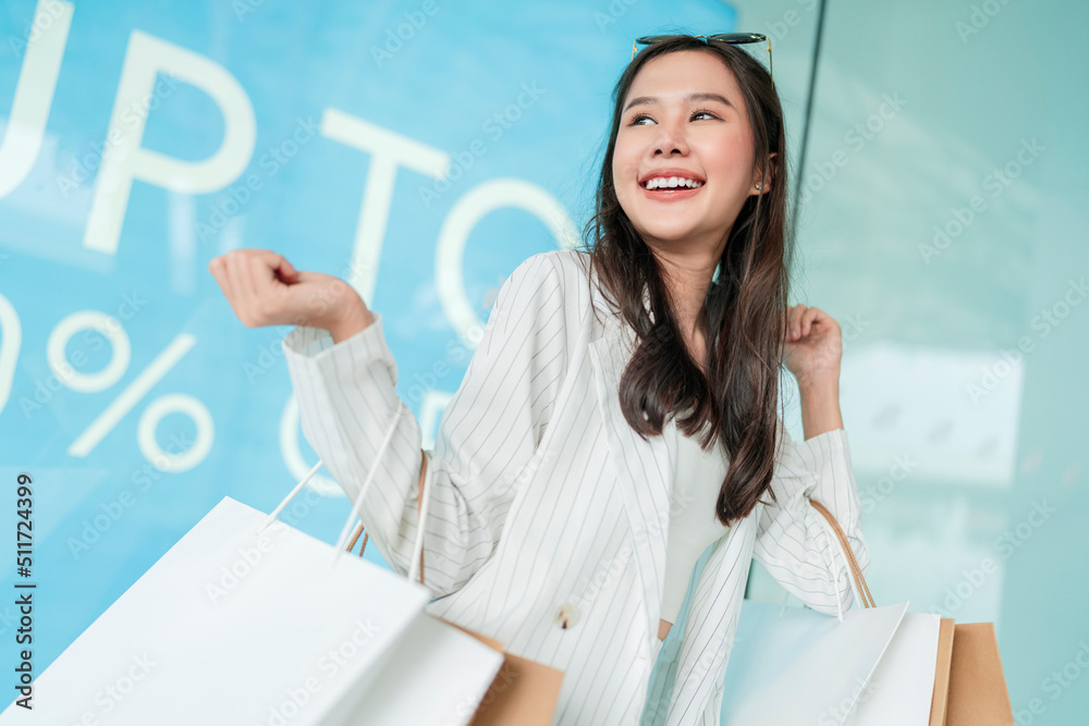 快乐微笑的亚洲女女孩拿着一堆购物袋，女性购物后回家