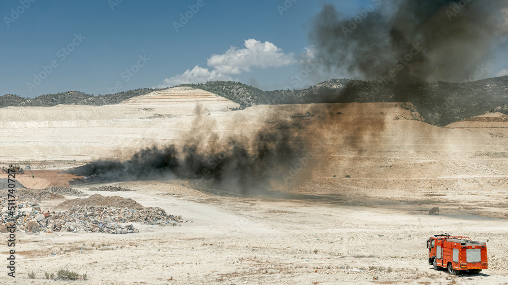 Fire fighting in a tire dump. Fire truck and black smoke from burning tires