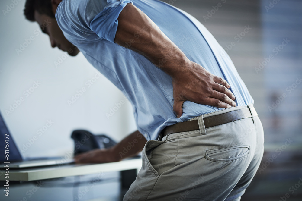 Its so painful I cant even stand up properly. Shot of a young businessman suffering with back pain a