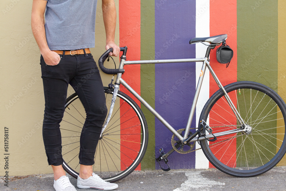 Do you like my ride. Cropped shot of a stylishly dressed young man standing next to a bicycle agains