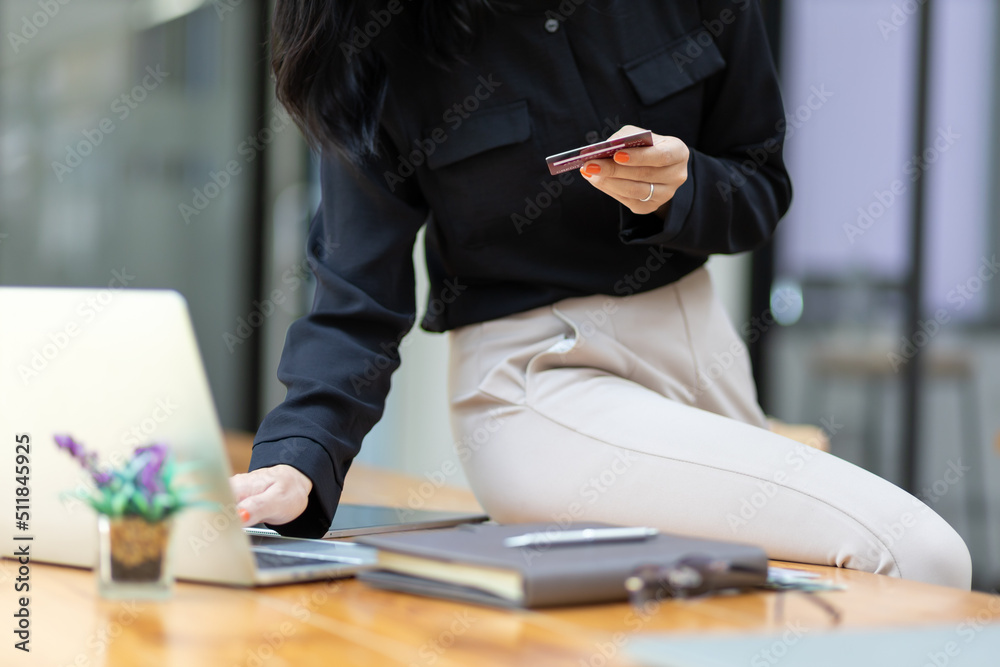 Attractive beautiful Asian woman holding a credit card using a laptop. Online payment and shopping c