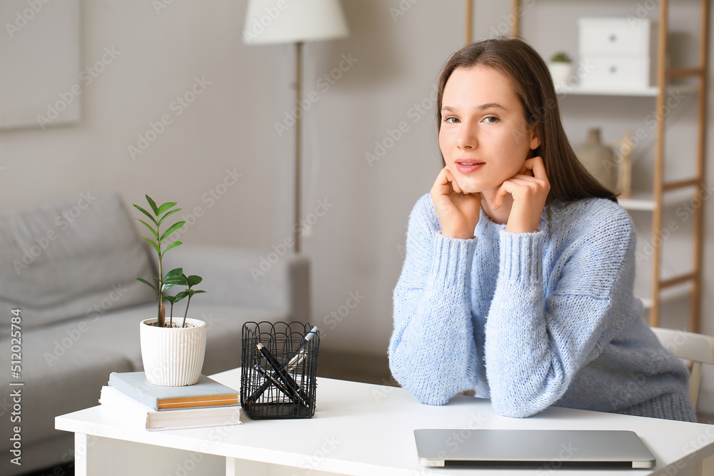 Pretty young woman sitting at table in room