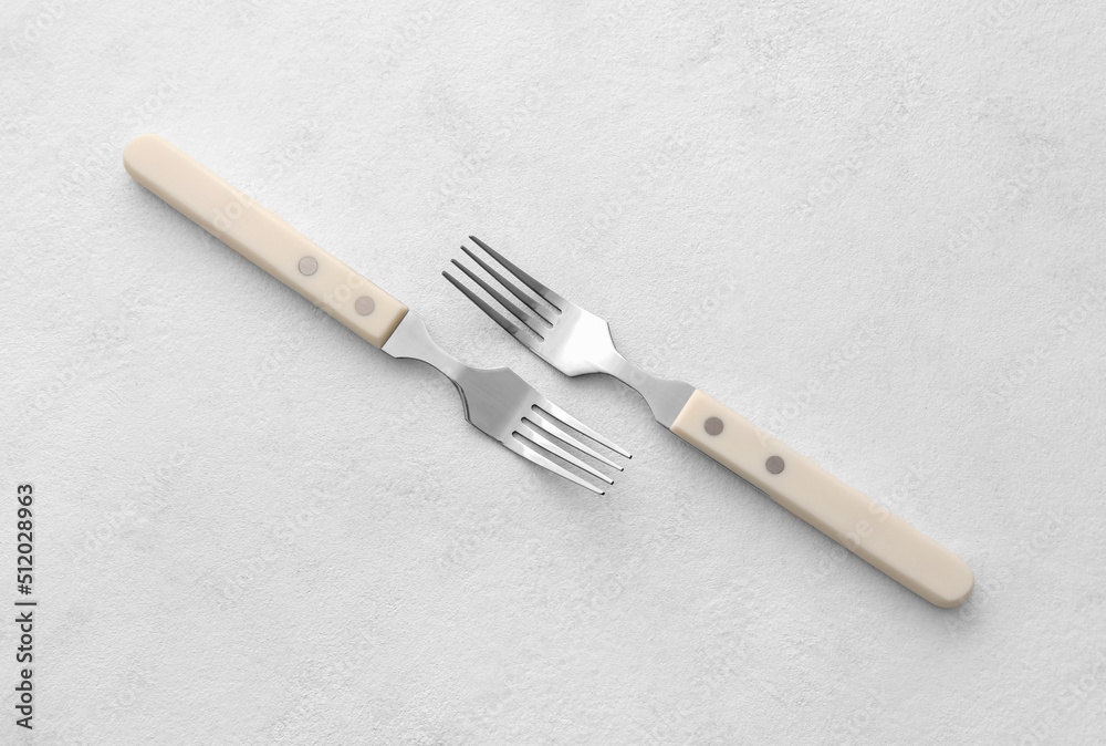 Stylish stainless steel forks on light background