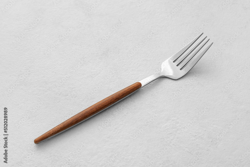 Stylish stainless steel fork on light background