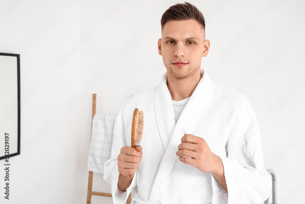 Young man with brush and fallen down hair in bathroom