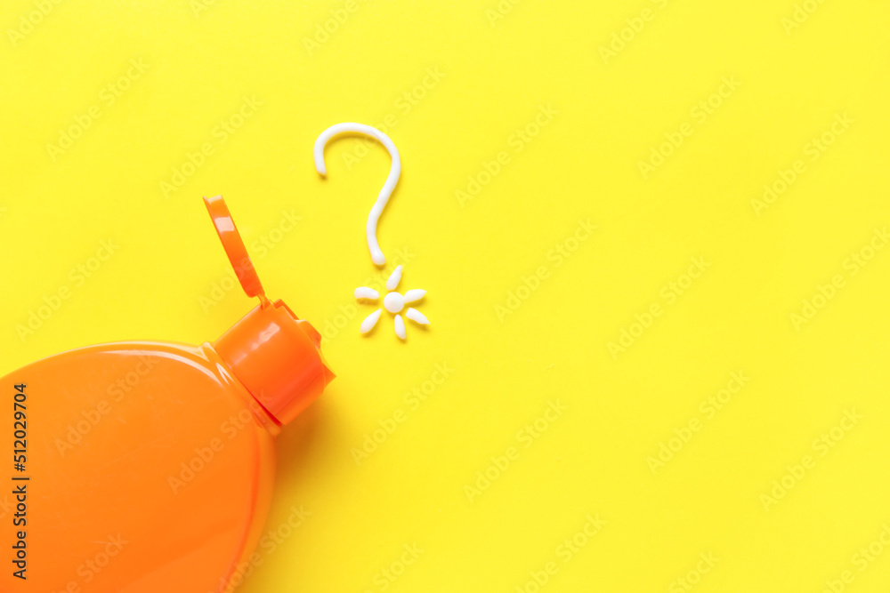 Bottle of sunscreen and question mark made of cream on yellow background