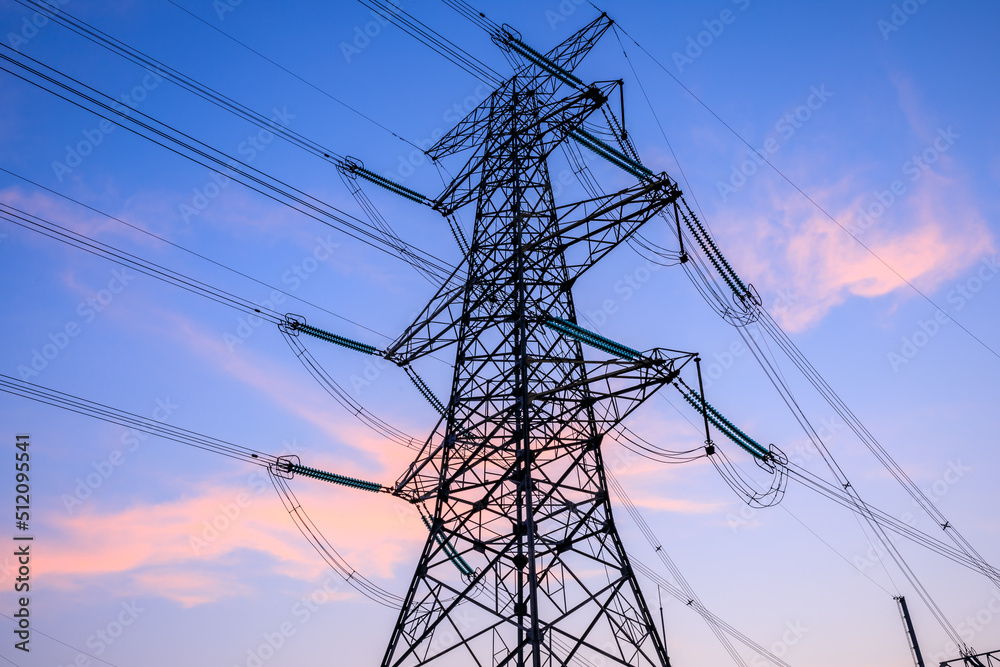 High voltage electric tower at sunset. Transmission power line. Electricity pylons and sky clouds ba