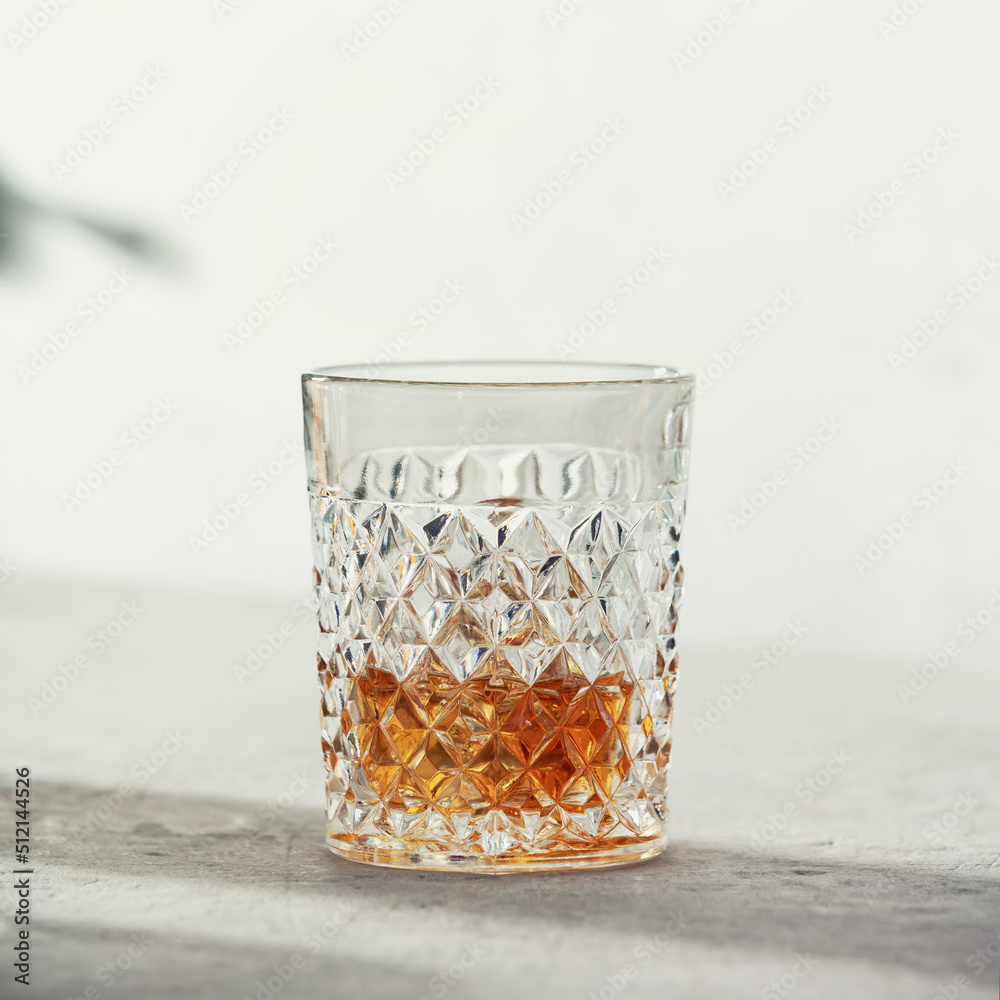 Glass of whiskey with ice cubes close up