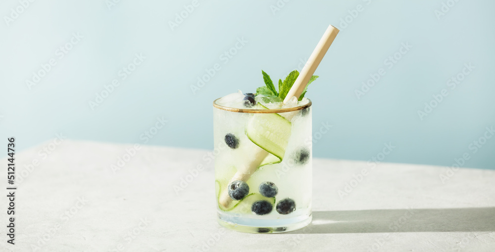 Trendy summer drinks with cucumber, mint and blueberry on blue sky background