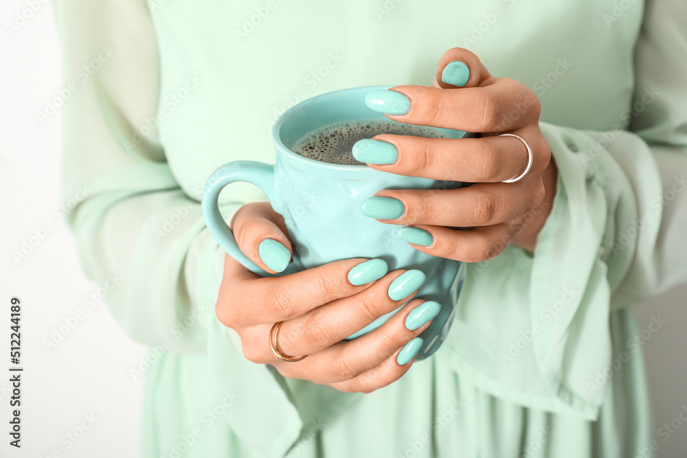 Woman with beautiful mint manicure and cup of coffee, closeup