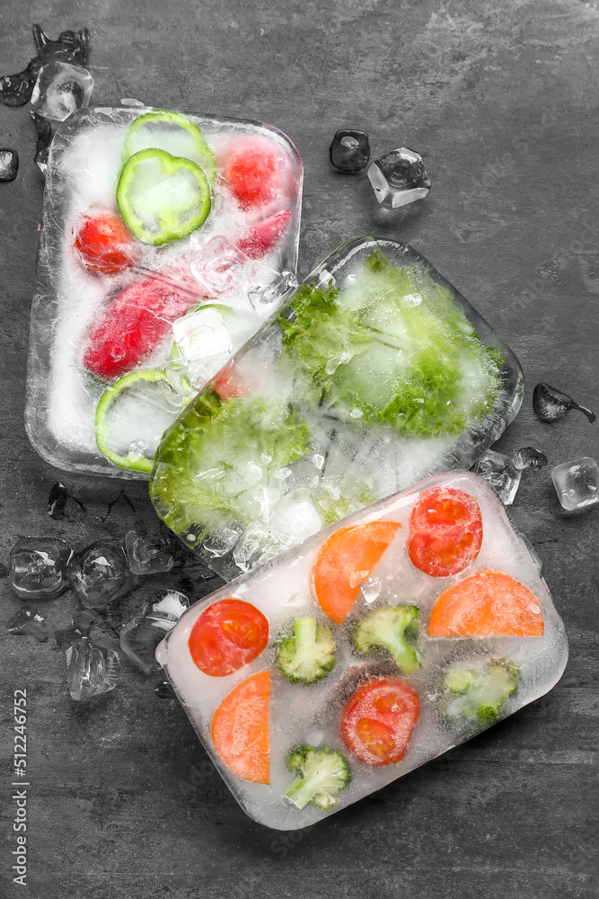 Fresh cut vegetables frozen in ice on black background