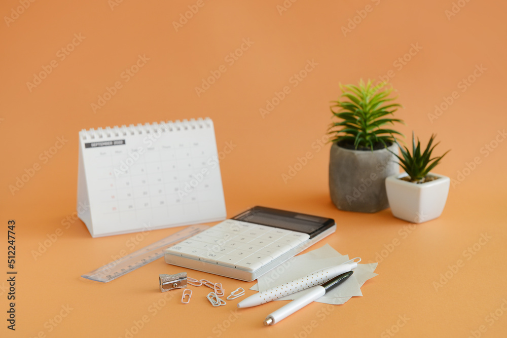 Different stationery and calendar on orange background