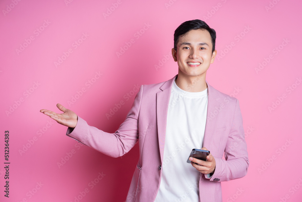 Portrait of young Asian man wearing pink suit posing on background