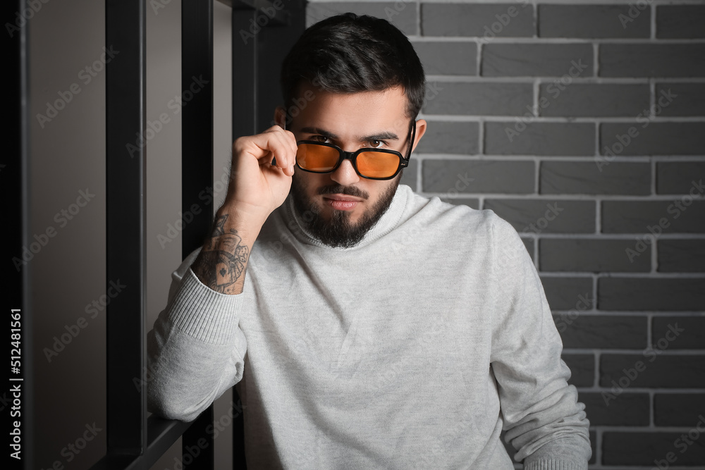 Bearded man wearing sunglasses near grey brick wall