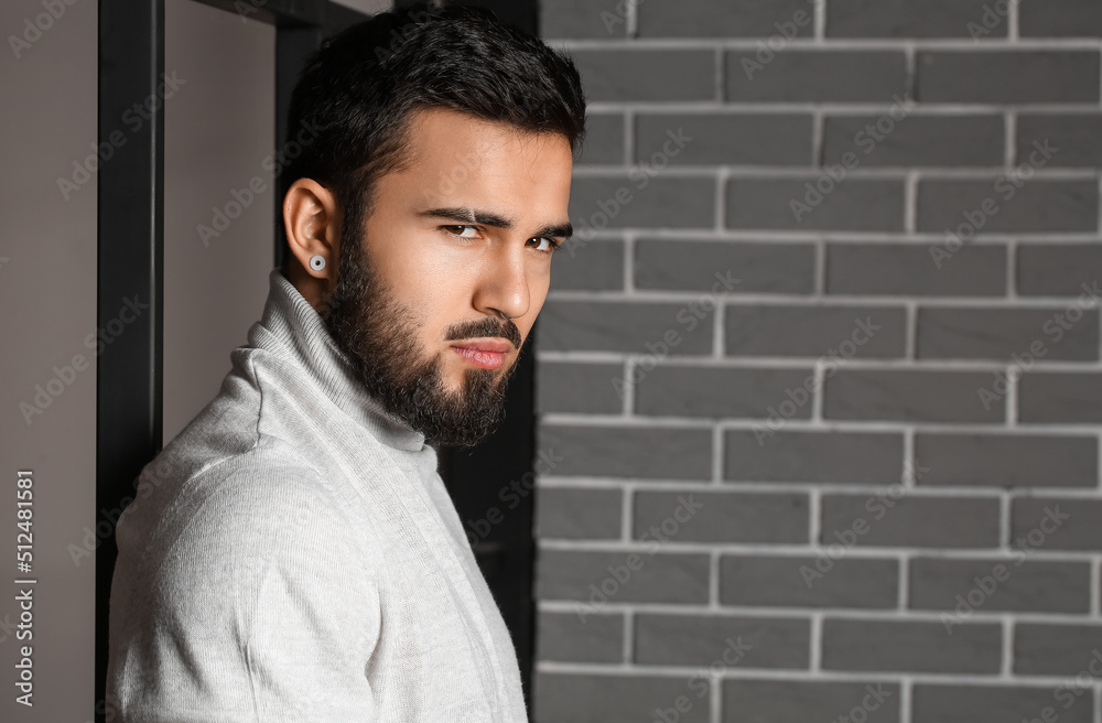 Fashionable bearded man near grey brick wall