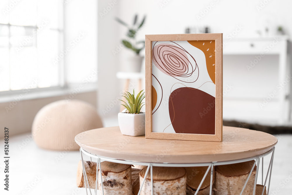 Stylish picture and flowerpot on table in room