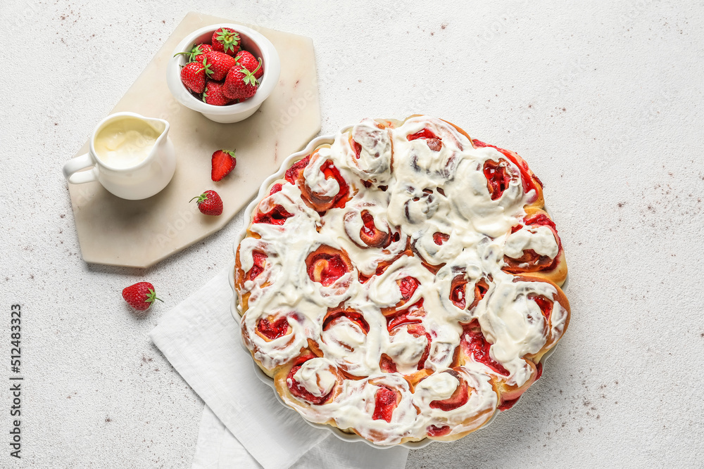 Baking dish with strawberry cinnamon rolls and cream on white background