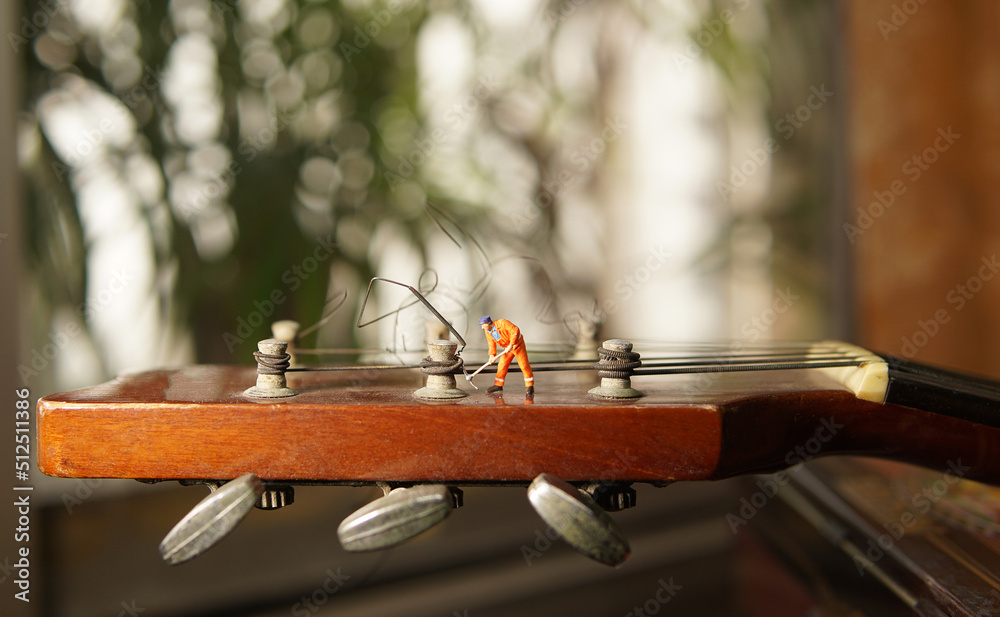 The technician worker figure fixing old guitar strings.