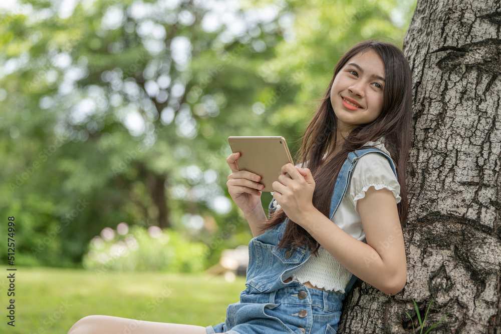 公园里体贴微笑的女人使用智能数字平板电脑，一位年轻迷人的商业女性的画像