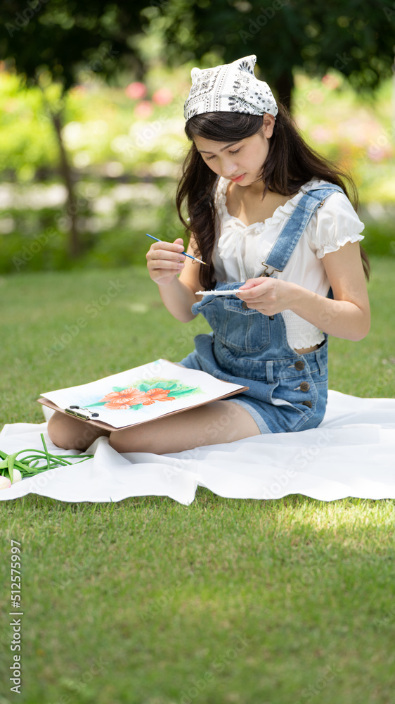 迷人的女孩在阳光明媚的夏天坐在公园的格子布上，用水彩完成