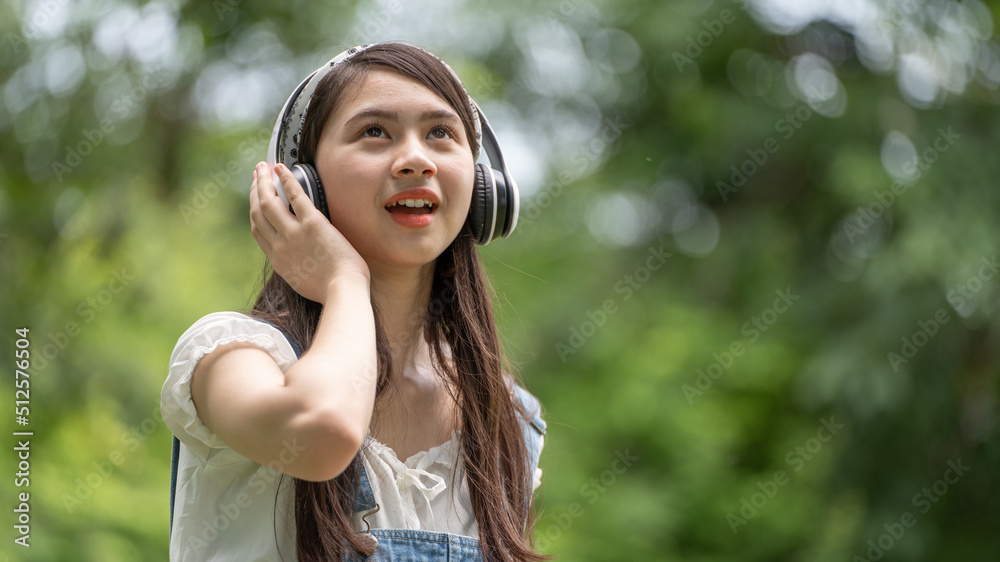 Beautiful young woman girl in beige shirt posing in Green city Park background , Smile girl Listenin