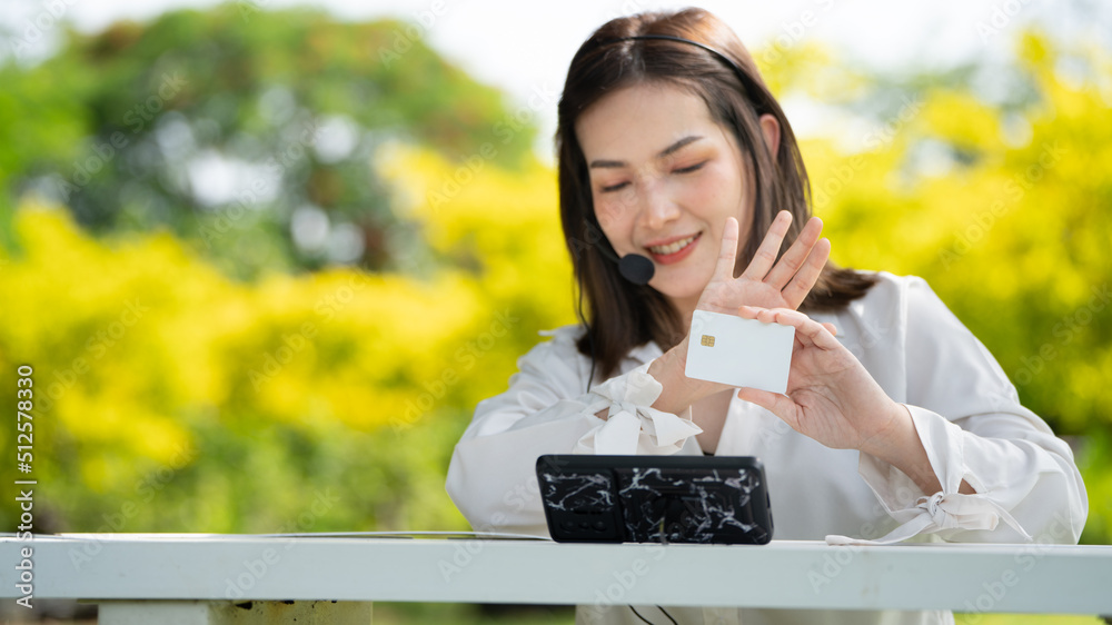 购物者微笑女孩坐在本上用智能手机和信用卡在网上购物或工作