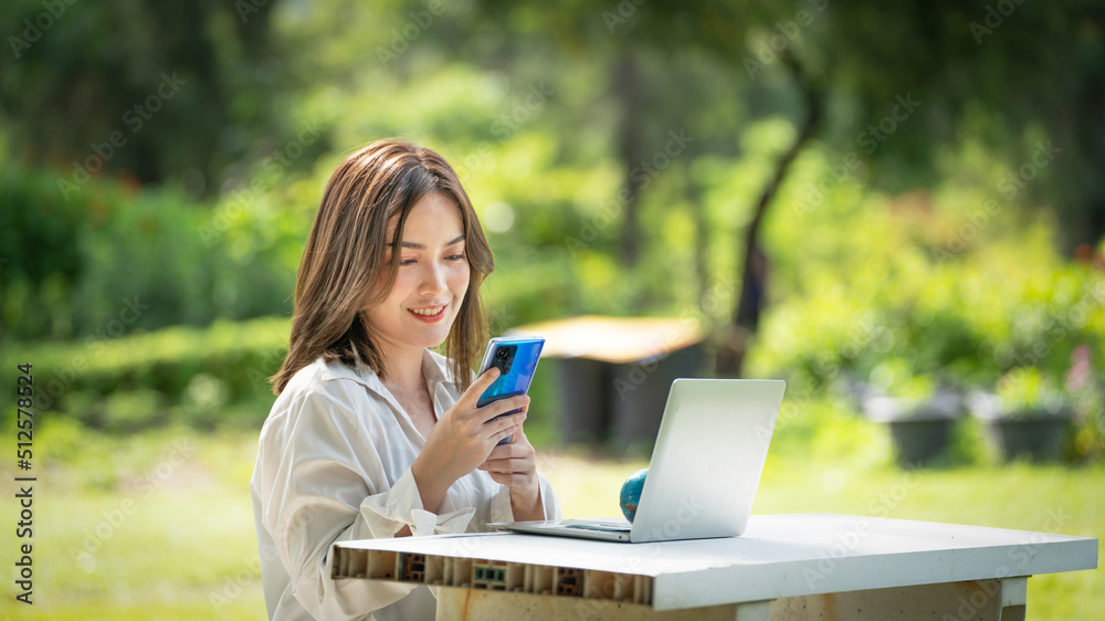 公园里体贴微笑的女人用智能手机，一位年轻迷人的商业女性的画像checki