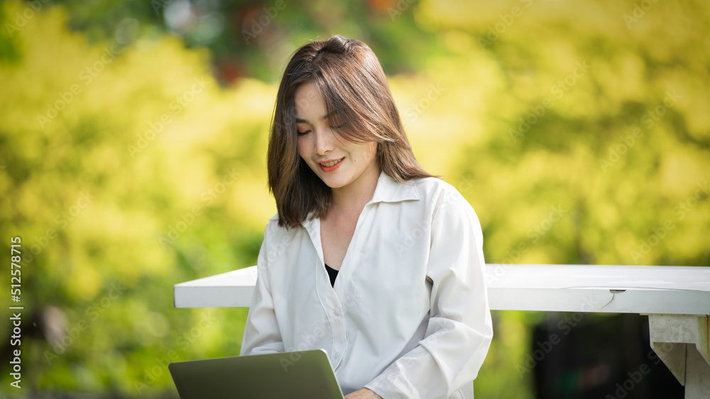 公园里体贴的微笑女人使用智能数字平板电脑，一位年轻迷人的商业女性的画像