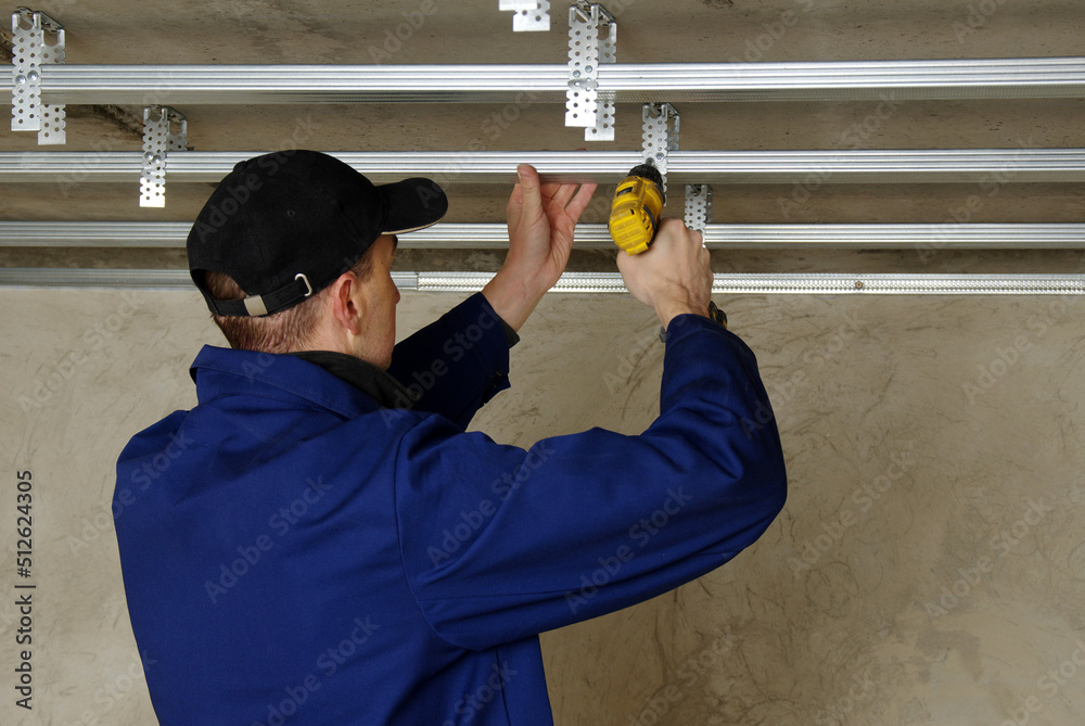 Man fasten metal profile frame to the ceiling for plasterboard installation