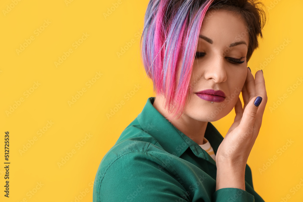 Beautiful woman with short dyed hair on yellow background, closeup