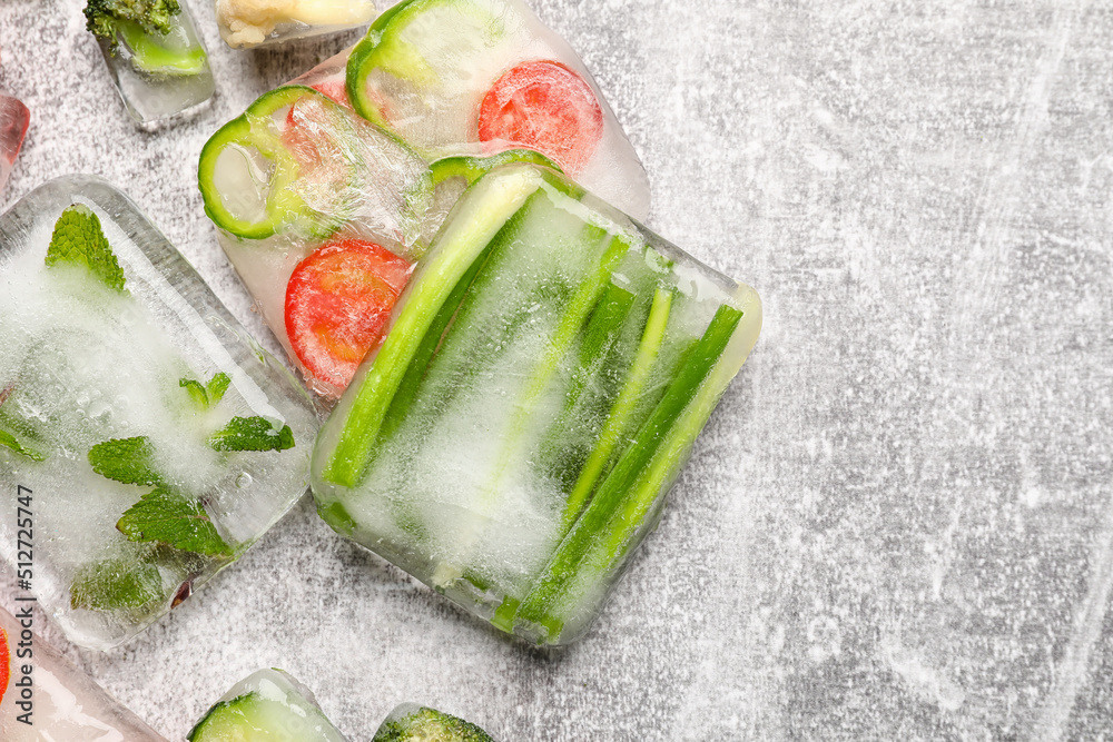 Fresh cut vegetables frozen in ice on grey background