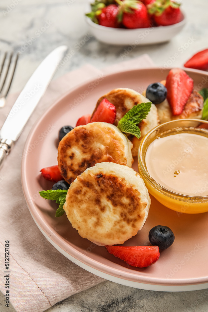 Plate with delicious cottage cheese pancakes, berries and honey on light background, closeup